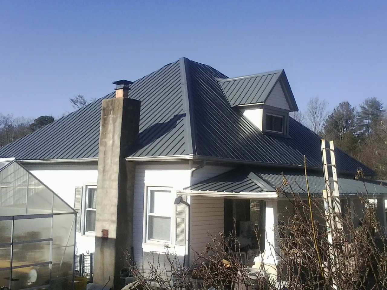 Dark blue standing seam metal roof on a white farmhouse with dormer — Slate & Tile Roof Repair by Roofing Brothers in Pinckneyville