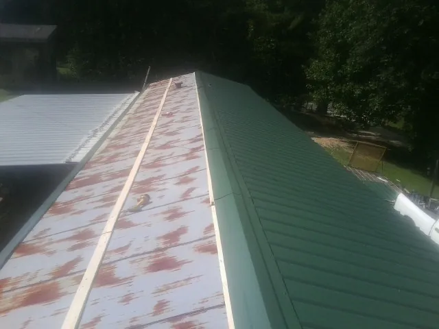 Old rusted panels beside newly installed green metal roofing — Wind Damage Roof Repair by Roofing Brothers in Pinckneyville