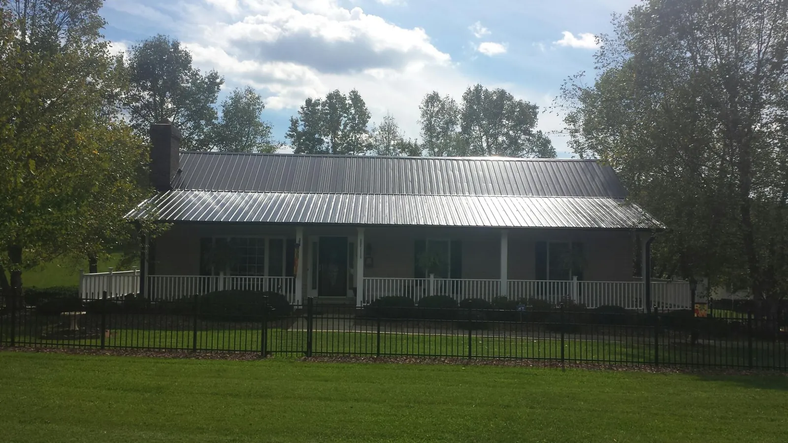 Gray metal roof on a brick ranch with a full width front porch — Gutter Guard Installation work by our crew in Pinckneyville