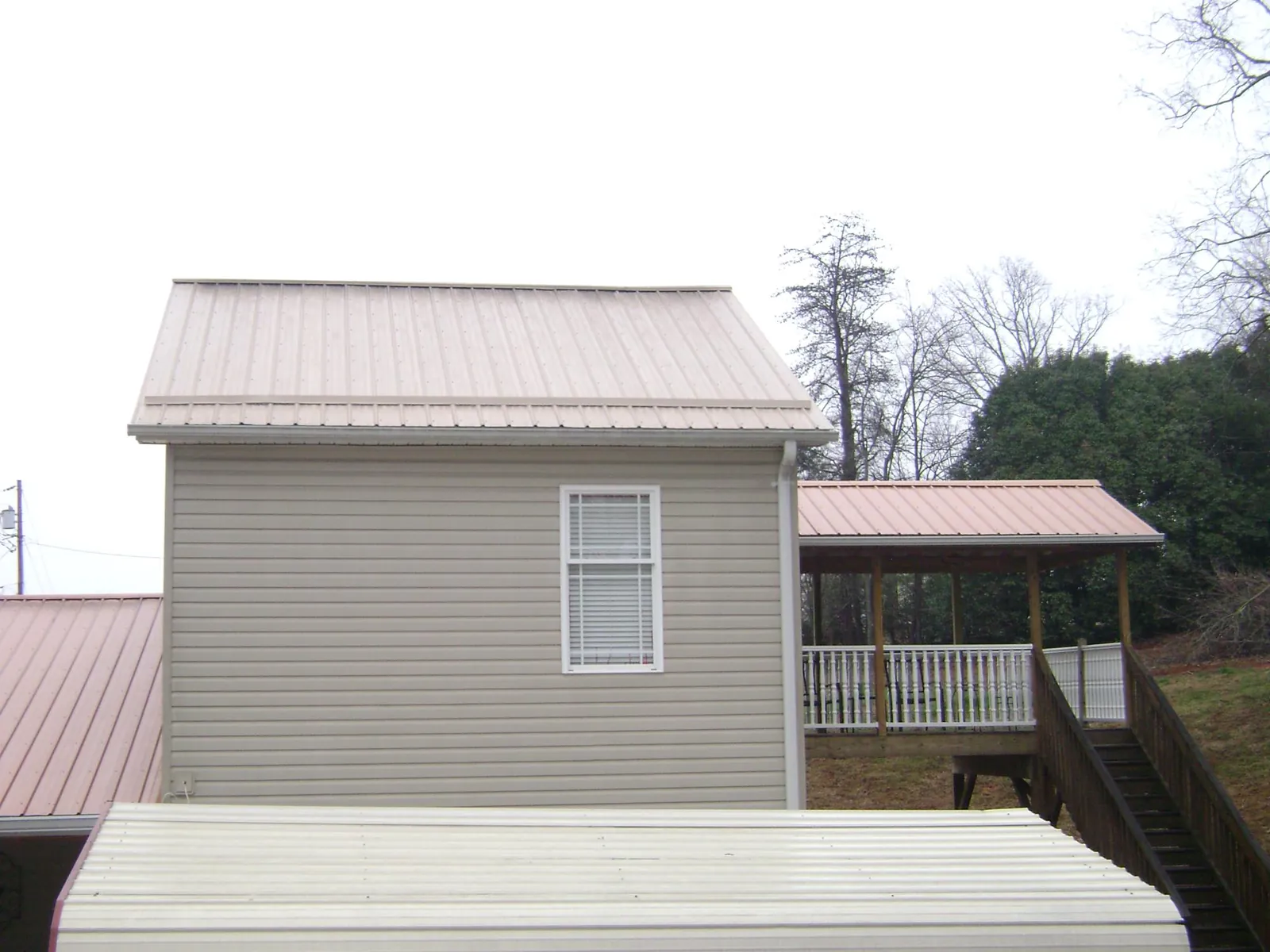Tan metal roofs on a two story addition and attached porch, from a Roof Replacement job in Pinckneyville